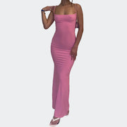 Person wearing a pink dress standing indoors with a plant and window in the background
